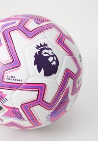 Puma fodbold med hvid bund, præget af livlige pink og lilla zigzag-mønstre. Inkluderer et fremtrædende lilla løve-logo. Struktureret overflade.