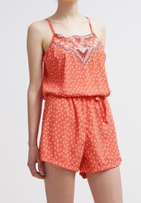 Kombinezon w koralowy wzór z cienkimi regulowanymi ramiączkami, ściągniętą talią z wiązanym detalem oraz dekoracyjnym haftem na górze.