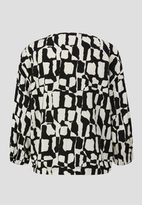 Blouse ample avec un motif abstrait noir et blanc, dotée de manches longues et de poignets froncés, fabriquée à partir d'un tissu lisse.
