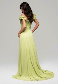 Abito da sera lungo di un verde lime, con un corsetto aderente, texture arricciata e dettagli floreali sulle spalle, gonna fluttuante che striscia a terra.