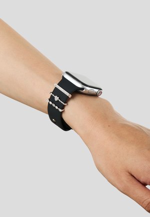 Smartwatch met zwarte band gedragen om de pols, versierd met drie zilveren ringen met diverse ontwerpen en ingelegde stenen.