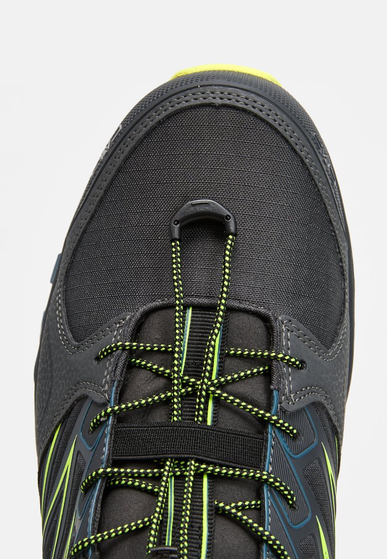 Scarpa atletica grigia con tomaia testurizzata, dotata di lacci e dettagli in nero e verde neon, punta rotonda e design aderente.