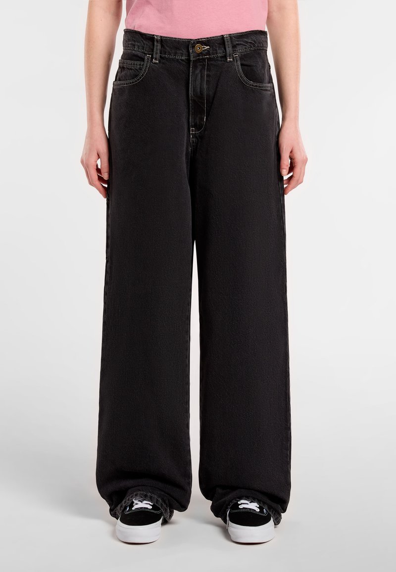 Black wide-leg jeans made of denim, featuring a high waist, front pockets, and subtle textured finish. Paired with black sneakers.