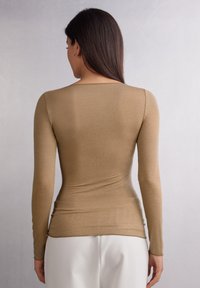 Aansluitend lang shirt met lange mouwen in lichtbruine ribstof, voorzien van een ronde halslijn en een slanke silhouet, met zijsplitten aan de zoom.
