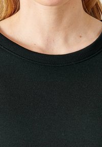Top a coste nera con scollatura ampia. Texture liscia con dettagli di cucitura visibili lungo il colletto. Nessun motivo o accento visibile.