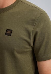 Olijfgroene T-shirt met korte mouwen, gemaakt van gestructureerde katoen, met een rechthoekig logo-label op de borst en een ronde hals.