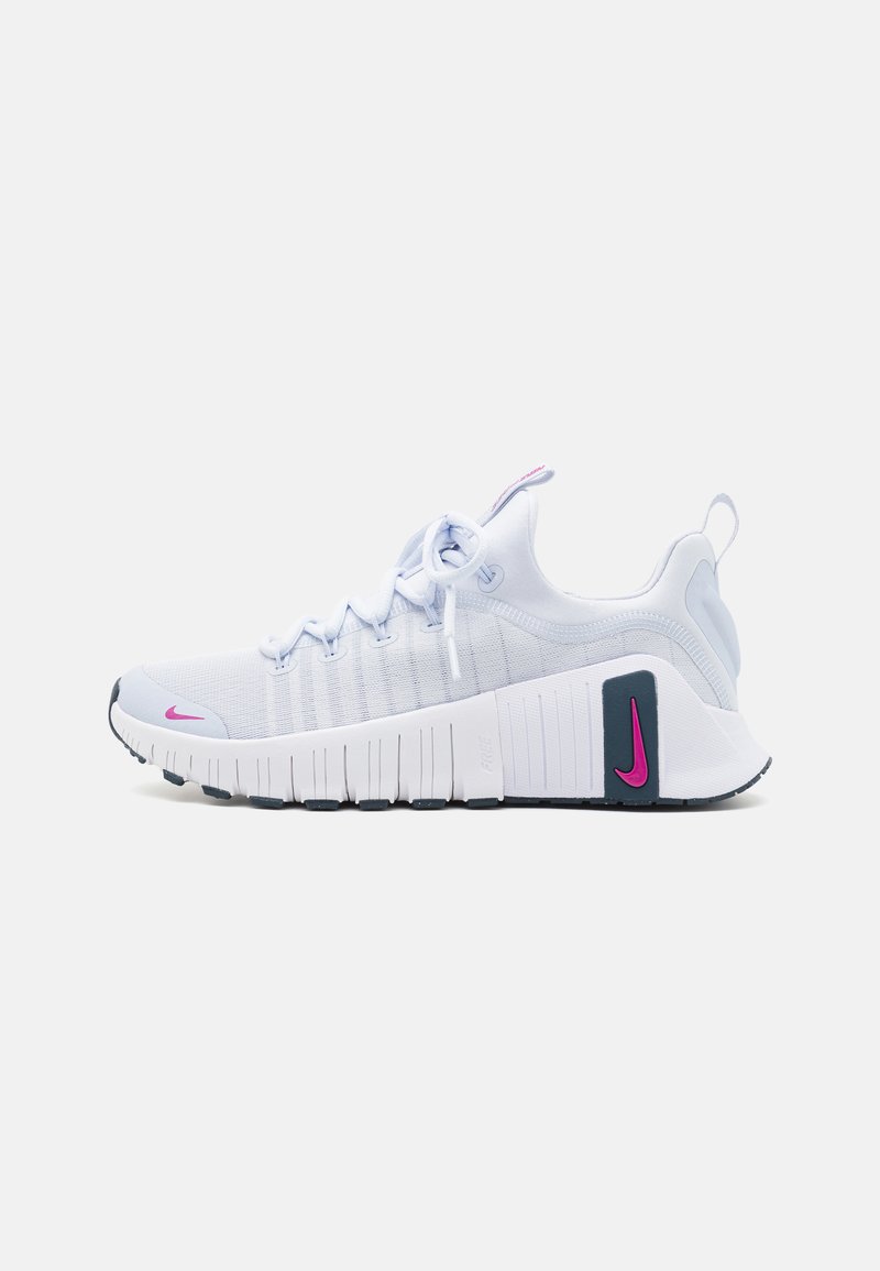 Hvit idrettssko med en teksturert overdel i stoff, rosa Nike-swoosh, fremtredende polstret såle og grå akcenter, designet for ytelse.