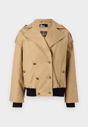 Sacou bej cu nasturi dubli, rever larg, butoni aurii, căptușeală interioară în carouri, manșete și tiv negre cu nervuri, și epoleți pe umeri.