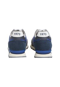 Kék és szürke sportcipők velúr felsőrésszel, fehér saroktáblával, rajta a "1973" felirattal, valamint egy gumitalppal, ami kontrasztos kék részleteket tartalmaz.