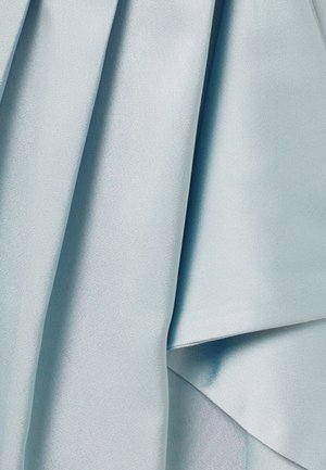 Tissu bleu clair doux à la texture lisse, présenté en plis et drapés délicats, mettant en valeur son mouvement et son éclat subtil.