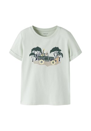 Camisa de manga corta verde claro con gráfico de un jeep de la selva que lleva una jirafa, una cebra y un perezoso, rodeados de árboles y un tigre al frente.