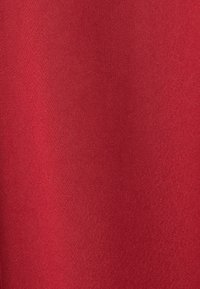 Gros plan d'un tissu rouge lisse avec une texture tissée fine et de subtiles variations d'ombrage.