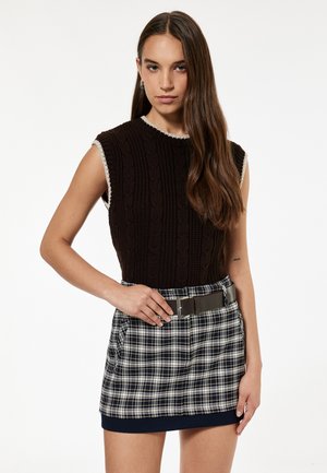 Brown knitted sleeveless top with a textured pattern and cream trim, paired with a plaid mini skirt featuring blue, white, and gray tones.
