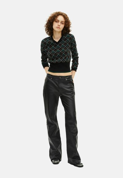 Maglione nero lavorato a maglia con motivo a diamante colorato, abbinato a pantaloni in pelle nera a vita alta. Entrambi i capi presentano un design aderente.