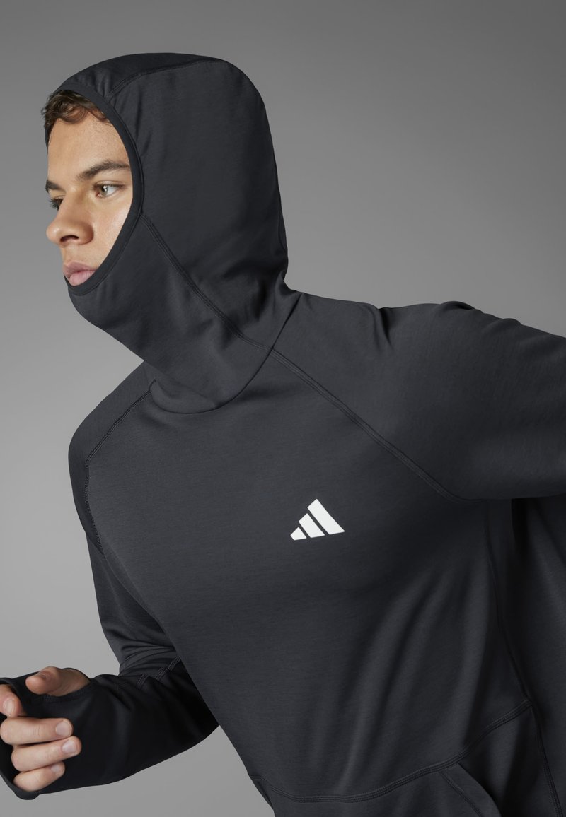 Crni dugosabni sportski majica s uskim kapuljačom, s Adidas logotipom. Glatka tkanina i vidljive šavove.