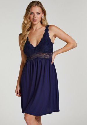 Navy Nachthemd mit einem Spitzenoberteil mit gewellten Kanten, verstellbaren Trägern und einem fließenden, weichen Rock, der oberhalb des Knies endet.