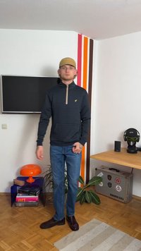 Pullover a mezza zip di un blu navy scuro con striature sottili, zip beige e polsini a coste, abbinato a jeans azzurri chiari e scarpe scure.