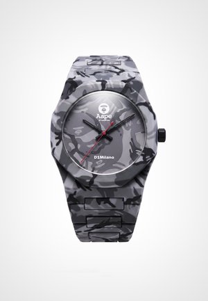 Montre-bracelet à motif camouflage gris et noir avec un cadran rond, aiguilles des heures et des minutes noires, aiguille des secondes rouge et logos de la marque sur le cadran.