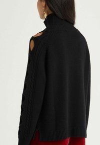 Pull noir en maille avec un col montant, des découpes aux épaules et un détail en torsades le long des manches. Texture douce, coupe décontractée.