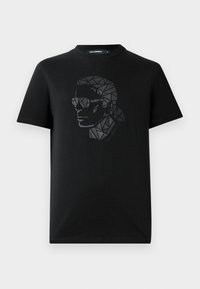 Camiseta de algodón negra con un diseño geométrico y reflectante en negro de una cara usando gafas de sol en el frente. Cuenta con un escote redondo.