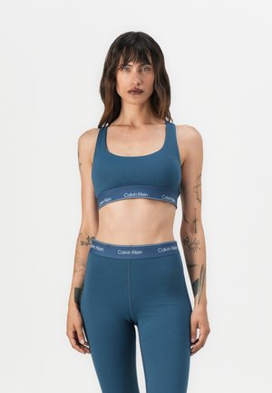 Sportski brus i tajice u tamnoplavoj boji, s okruglim izrezom i Calvin Klein detaljima u obliku loga na struku.