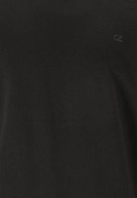 Svart bomull t-shirt med korta ärmar och rundad halsringning. Har en diskret logotyp tryckt i en något mörkare nyans på bröstet.