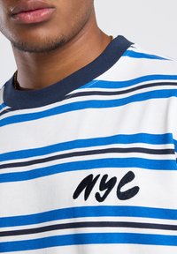 Cotton t-shirt featuring blue and white horizontal stripes, navy ribbed collar, and black embroidered "NYC" detail on the front.
