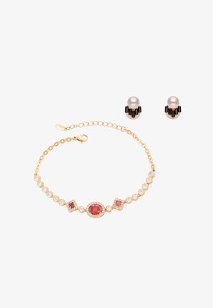 Braccialetto d'oro con tre pietre rosse circondate da piccole pietre trasparenti, abbinato a orecchini a lobo con perle e pietre nere.
