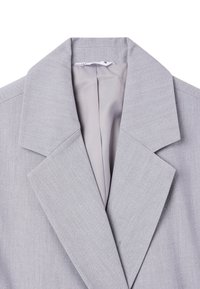 Blazer grigio con colletto strutturato, texture liscia e linee pulite; presenta un motivo di tessuto sottile e una leggera fodera visibile sul collo.