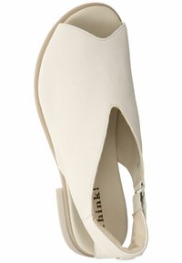 Světlé béžové sandály s otevřenou špičkou vyrobené z texturované kůže, s designem ve tvaru V a nízkým podpatkem se zabezpečovacím páskem kolem kotníku.