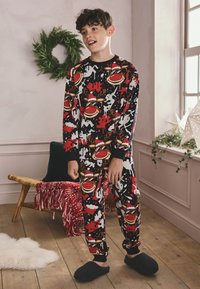 Sort pyjamasæt med et farverigt mønster af trommer, sprøjt og ferietemaer, med ribbede manchetter og en afslappet pasform. Blød stoftekstur.