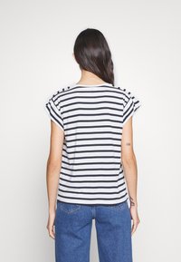 Camiseta a rayas en gris y azul marino, de manga corta, con cuello redondo, fabricada en tejido suave. Presenta puños enrollados. Vista trasera con un corte relajado.