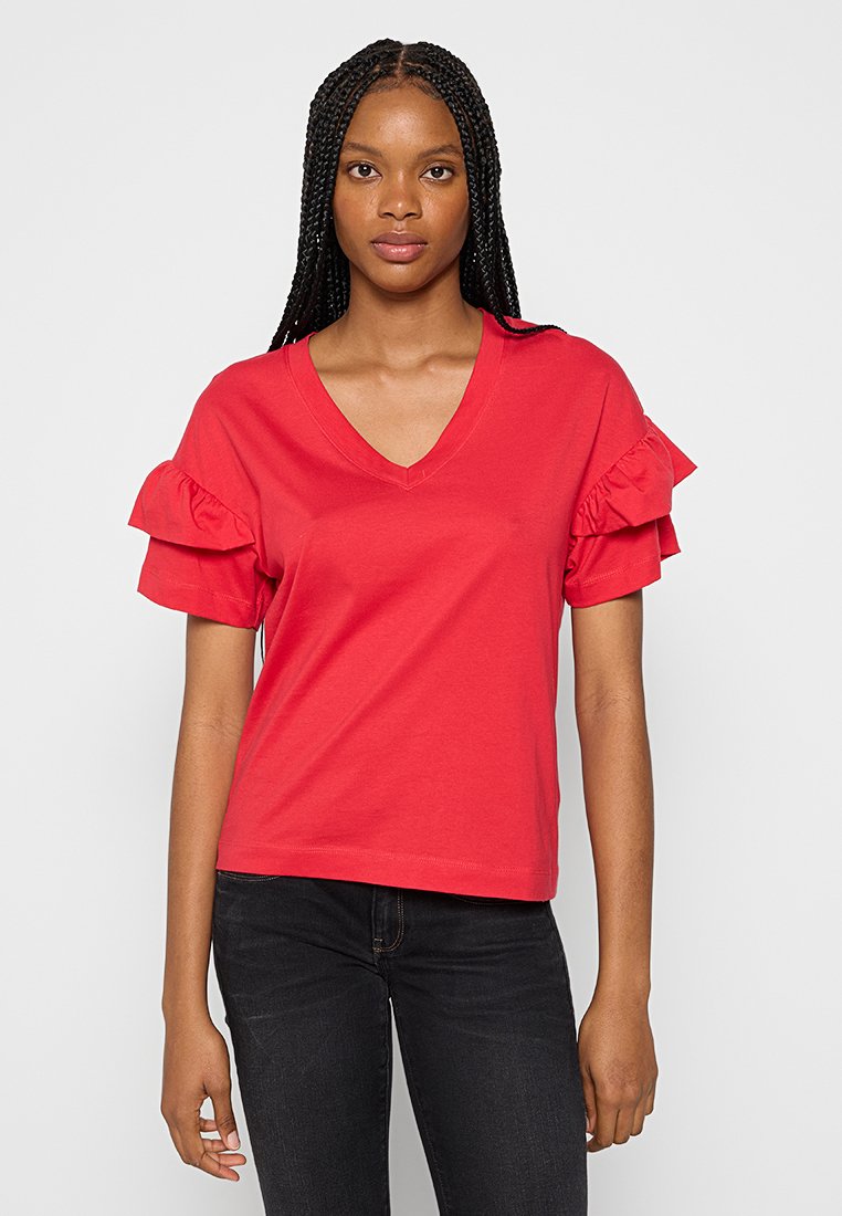 Rotes V-Ausschnitt-T-Shirt mit rüschenbesetzten kurzen Ärmeln, aus weichem Baumwollstoff hergestellt. Der Schnitt ist lässig, und die Farbe ist hell und lebendig.