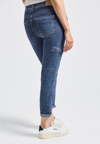 Dunkelblaue Denim-Jeans mit schlanker Passform, gekrempelten Säumen, zwei Gesäßtaschen und einer seitlichen Tasche im Cargo-Stil.