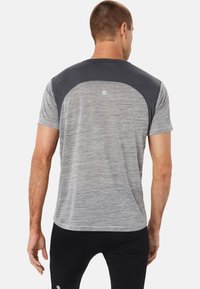 T-shirt sportivo grigio con pannelli grigi scuri sulle spalle, maniche corte e una trama melangiata, abbinato a pantaloni neri attillati.