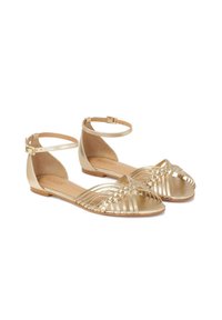 Goldene flache Sandalen mit geflochtenem Design, Knöchelriemen mit Schnalle und offener Zehenpartie. Glatte Ledertextur mit minimalistischer Optik.