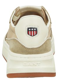 Beige und cremefarbene Sneaker mit strukturiertem Wildleder-Finish, gepolstertem Fersenbereich, Logo-Patch und kontrastierender Gummisohle.