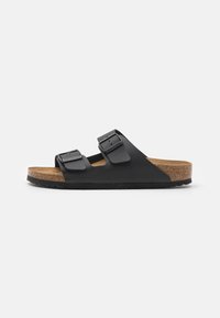 Black slide sandal featuring two adjustable buckled straps, cork footbed, and rubber outsole with textured tread for grip.