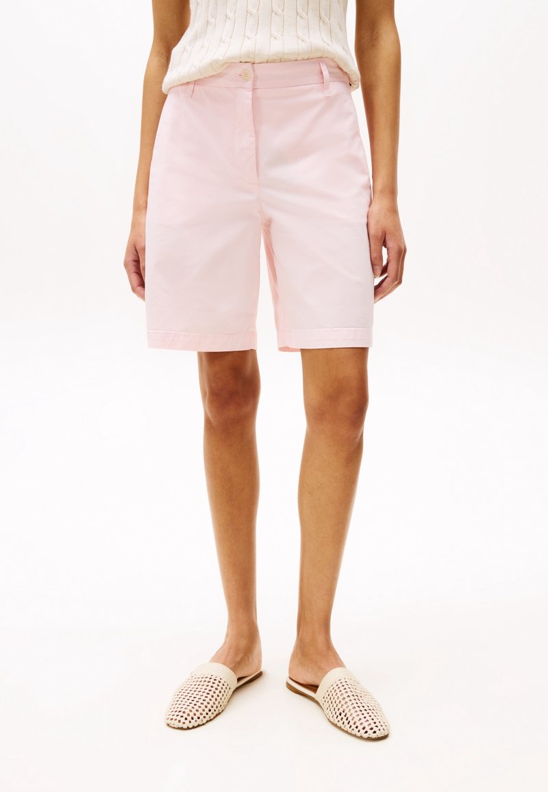 Rosa Baumwollshorts mit geradem Schnitt, ausgestattet mit einem Knopfverschluss und umgeschlagenem Saum, kombiniert mit geflochtenen Slippers.