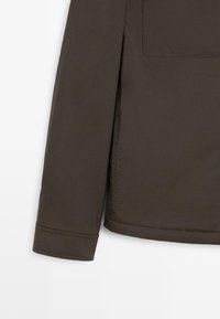 Brun, lätt jacka med elegant design, långa ärmar och en bröstficka. Slät textur och rak fåll med sydda detaljer.