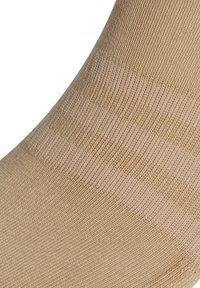 Chaussette beige avec une texture côtelée, une finition lisse et de subtiles rayures horizontales, fabriquée à partir d'un tissu extensible pour le confort.