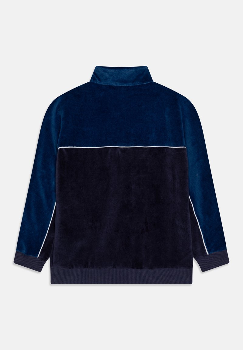 Pull-over en polaire douce bleu marine avec un col montant, des passepoils bleus clairs contrastants sur les épaules et des poignets et un ourlet côtelés.