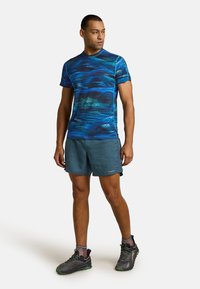 Athletic shirt in blue with wave patterns, paired with dark blue shorts. Features include short sleeves and a round neckline, lightweight material.