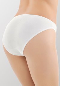 Perizoma in cotone bianco con una texture liscia, caratterizzato da un design a vita bassa e un elastico in vita. Senza motivi né accessori.