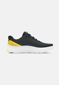 Baskets de sport noires avec une tige en mesh, accents jaunes, une semelle blanche et des détails texturés. Présentent un embout arrondi et un système de laçage.