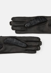 Luvas de couro pretas com textura suave, apresentando um patch protetor com padrão de crocodilo preto na palma. Design de quatro dedos.