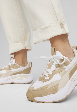 Baskets légères en mélange de matériaux beige et blanc. Comprend un daim texturé, des panneaux lisses et des lacets blancs.