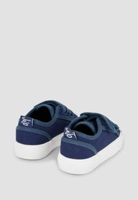 Scarpe in tela blu navy con chiusura a lacci e velcro, suole in gomma bianche e texture liscia, con un logo sulla parte posteriore.