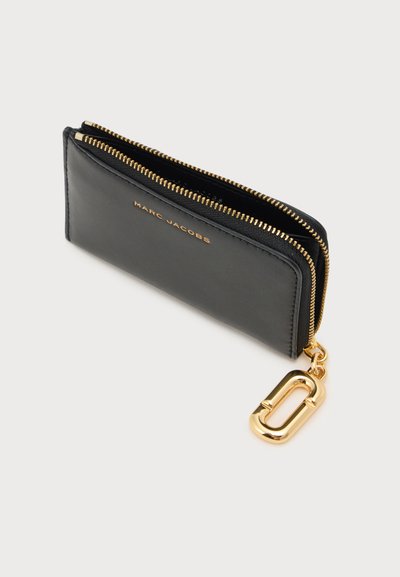 Portefeuille noir Marc Jacobs avec deux fermetures éclair dorées et un porte-clés ovale doré sur fond blanc.