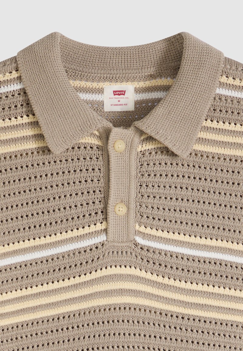 Polo en maille beige avec des rayures horizontales beige, crème et blanches, deux boutons beiges et une étiquette Levi's à l'intérieur du col.